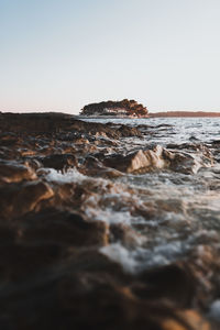 Surface level of rocks on shore against clear sky