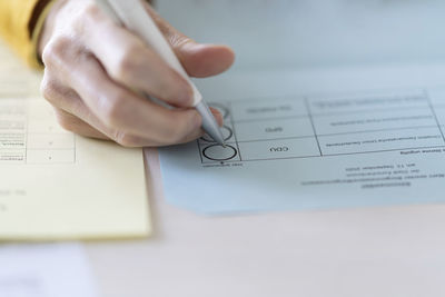 Close-up of woman filling voting ballot at home