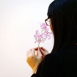 Close-up of woman holding flowers against white background