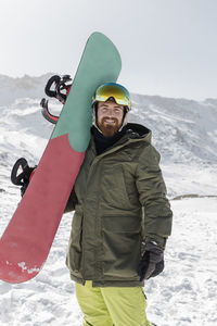 Smiling young man standing with snow board