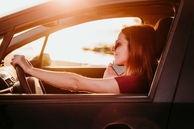 Woman sitting in car and using smartphone