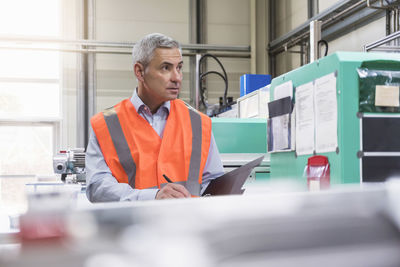 Engineer examining with file folder in factory