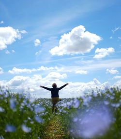 Rear view of man standing by plants against sky