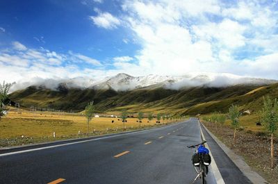 Man riding motorcycle on road against sky