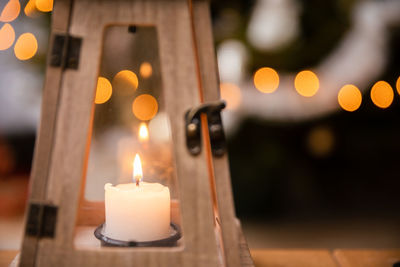 A candle burns closed inside a decorative lantern on christmas day.