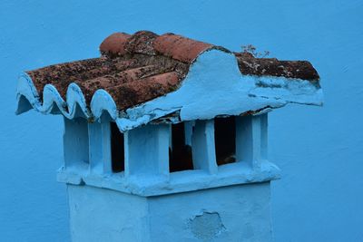 Close-up of damaged chimney by wall