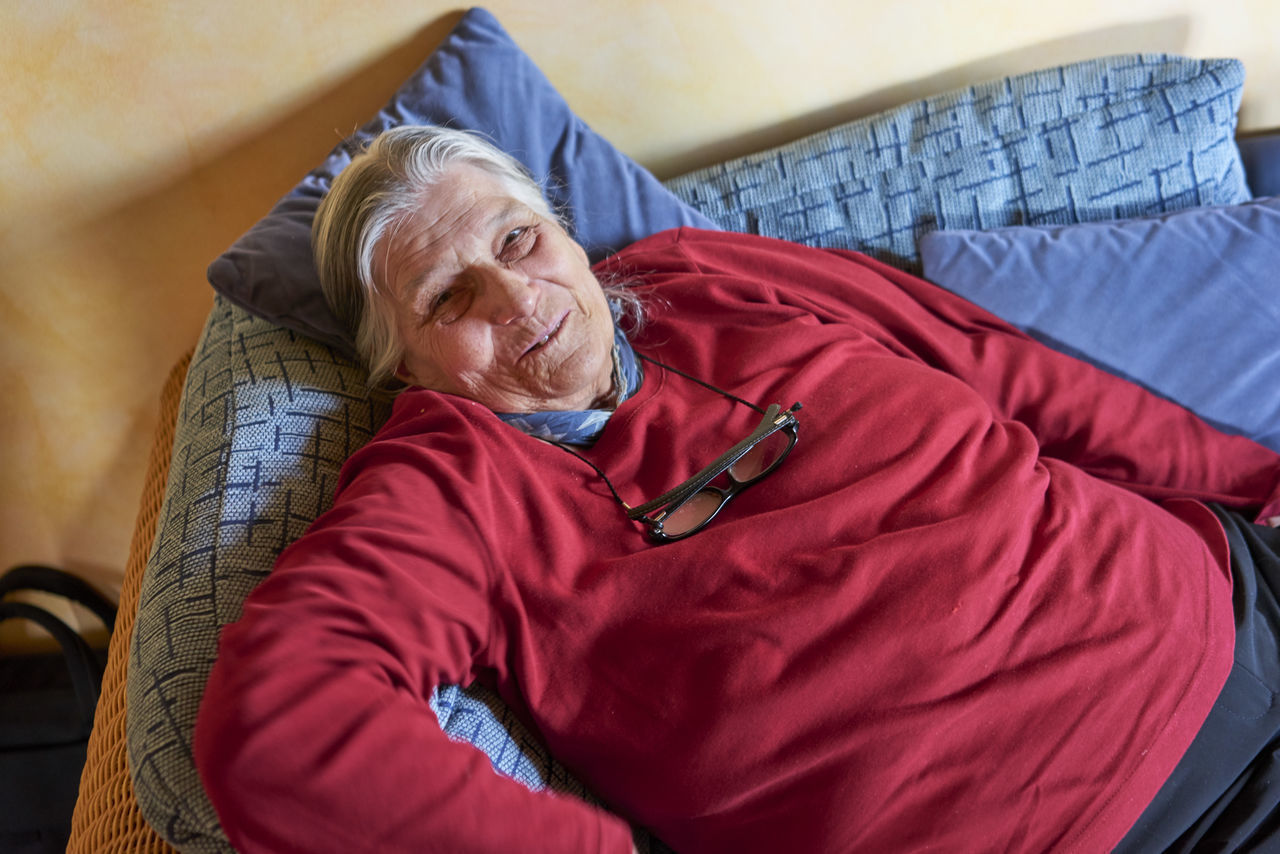 PORTRAIT OF SMILING MAN SITTING ON SOFA AT HOME