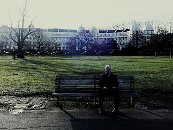 Man sitting on grass against sky