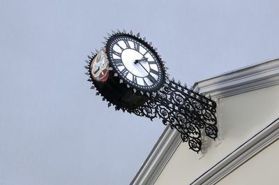 Low angle view of clock against sky