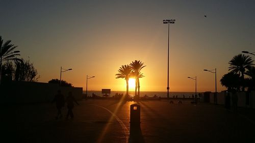 Silhouette man on road against sky at sunset