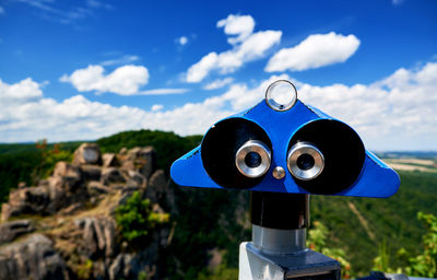 Close-up of coin-operated binoculars against blue sky