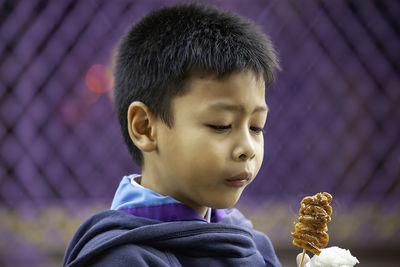 Close-up of boy holding food against wall