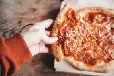 Large slice of pepperoni pizza in hands, close-up. delicious italian snack. pizza with salami.
