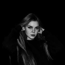 Portrait of young woman with long hair against black background