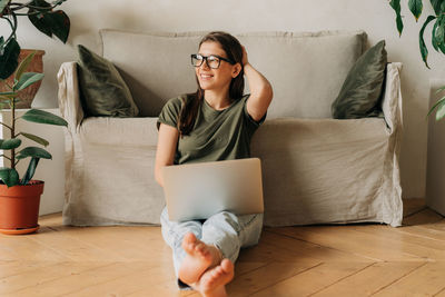 Young woman using phone while sitting on bed