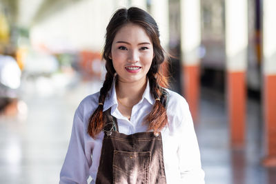 Portrait of young woman standing against railing