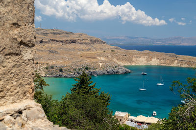 Scenic view from the acropolis on a bay and a beach with blue and turquoise water in lindos 