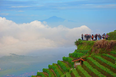 People standing on mountain against sky