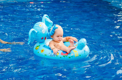 Woman with baby boy on inflatable ring swimming in pool