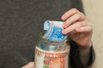 Midsection of woman removing paper currency from jar