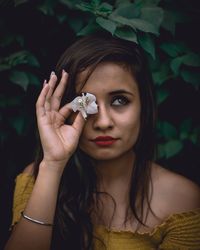 Portrait of young woman holding plant