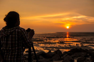 Rear view of man looking at sea during sunset