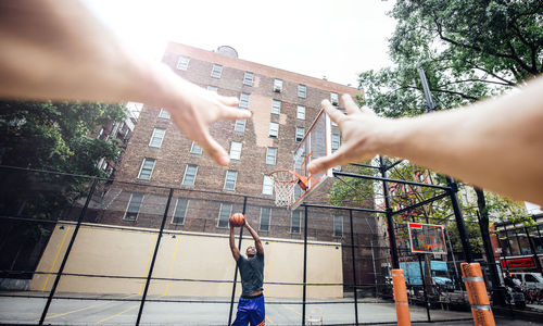 Cropped hands of person against man playing basketball at court