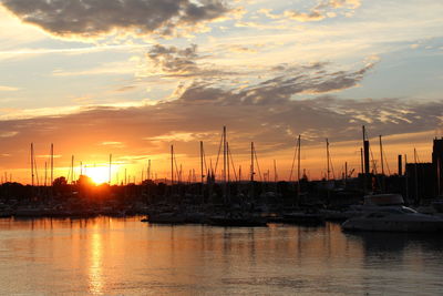 Sailboats moored at harbor during sunset