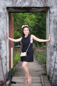 Portrait of young woman standing against old building