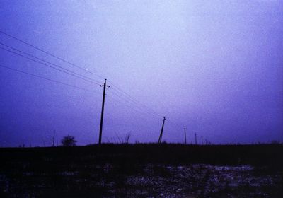 Low angle view of electricity pylon on field against sky