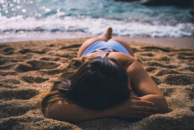 Rear view of woman relaxing on beach