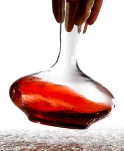 Close-up of hand holding red pouring over white background