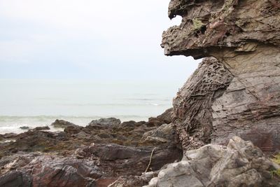 Rock formation by sea against sky