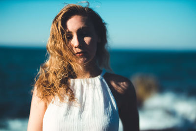 Close-up of beautiful woman standing at beach against sky