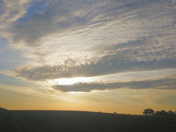 Scenic view of silhouette field against sky at sunset