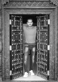 Portrait of young man standing against door