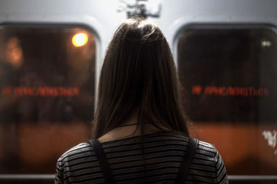 Rear view of woman standing against train