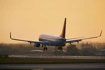 Airplane approaching for landing on airport runway. passenger plane at golden light of sunset. 