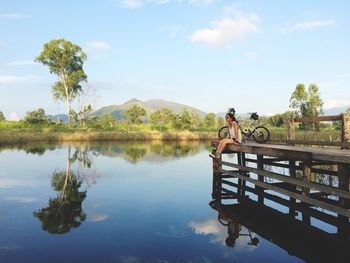 Young woman sitting on pier over lake