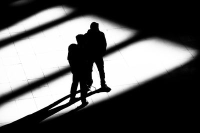 High angle view of silhouette men walking on tiled floor