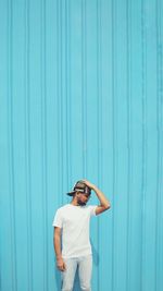 Young man standing against blue wall