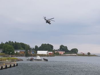 Helicopter flying over river against sky