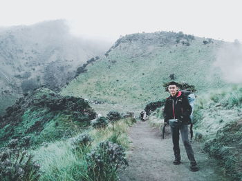 Portrait of man standing on footpath against mountain