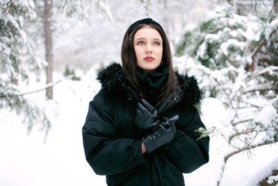 Portrait of young woman standing against trees