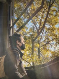 Side view of young woman looking through tree