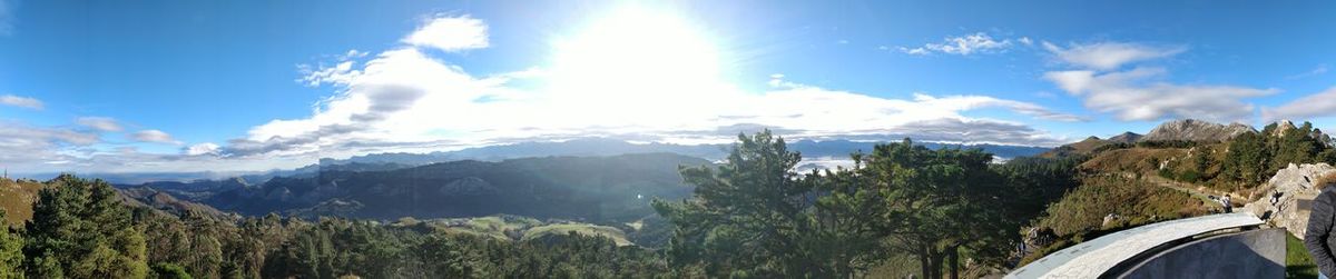 Panoramic view of trees and mountains against blue sky