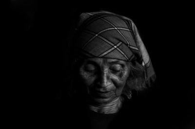 Close-up portrait of a woman against black background