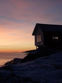 House by sea against sky during sunset