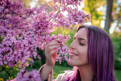 Portrait of woman with pink flowers against tree