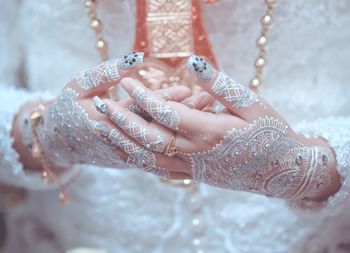 Midsection of bride in wedding dress with hands clasped